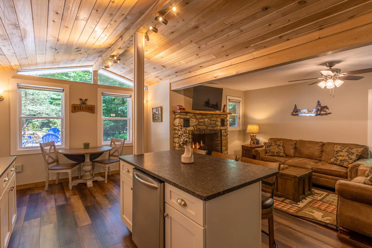 An open-plan living and kitchen area with a kitchen island, an additional fireplace, and large windows letting in natural light. The space feels inviting and sociable, ideal for sharing meals or planning the next day's explorations together.